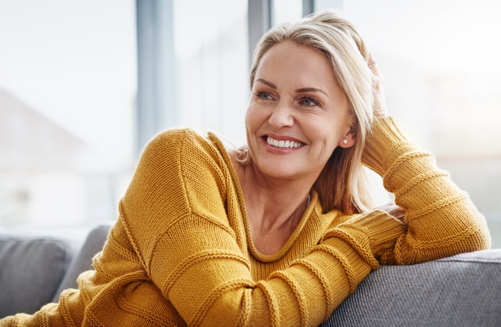 mature woman smiling on couch, perfect white teeth