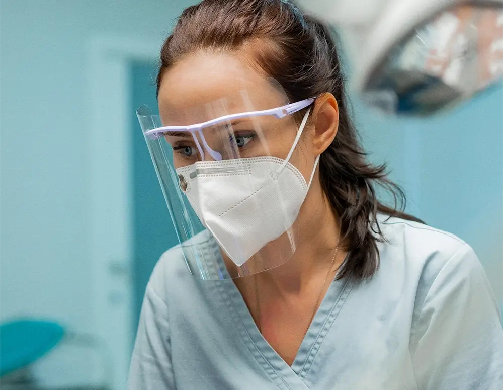 Female dentist wearing face guard and mask in office